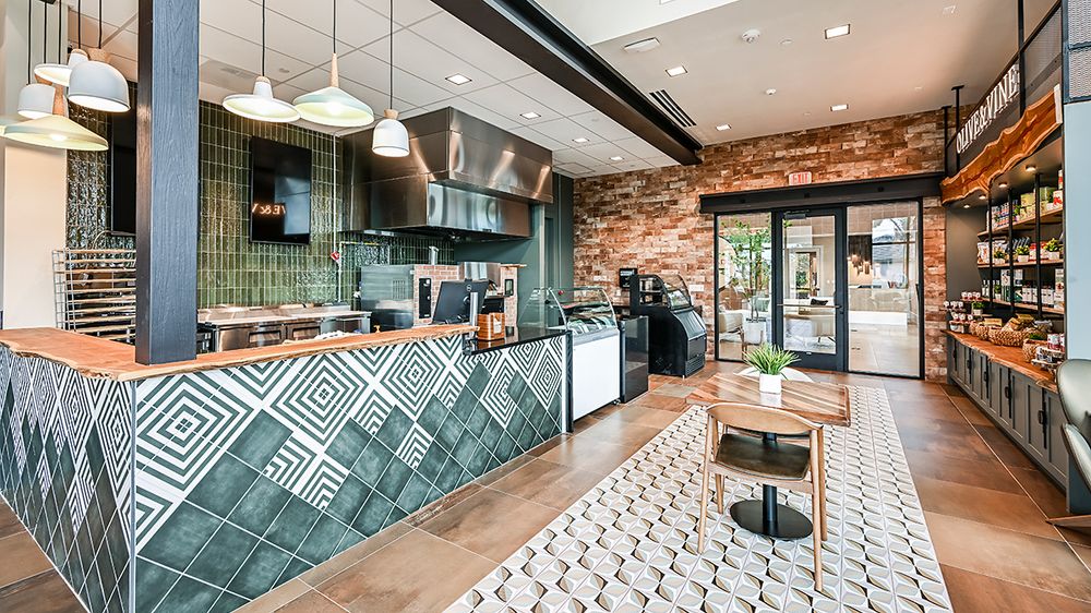 Esplanade Culinary Center interior with open kitchen and cafe seating, representative of the culinary program planned for Esplanade at Kingston in Estero, Florida